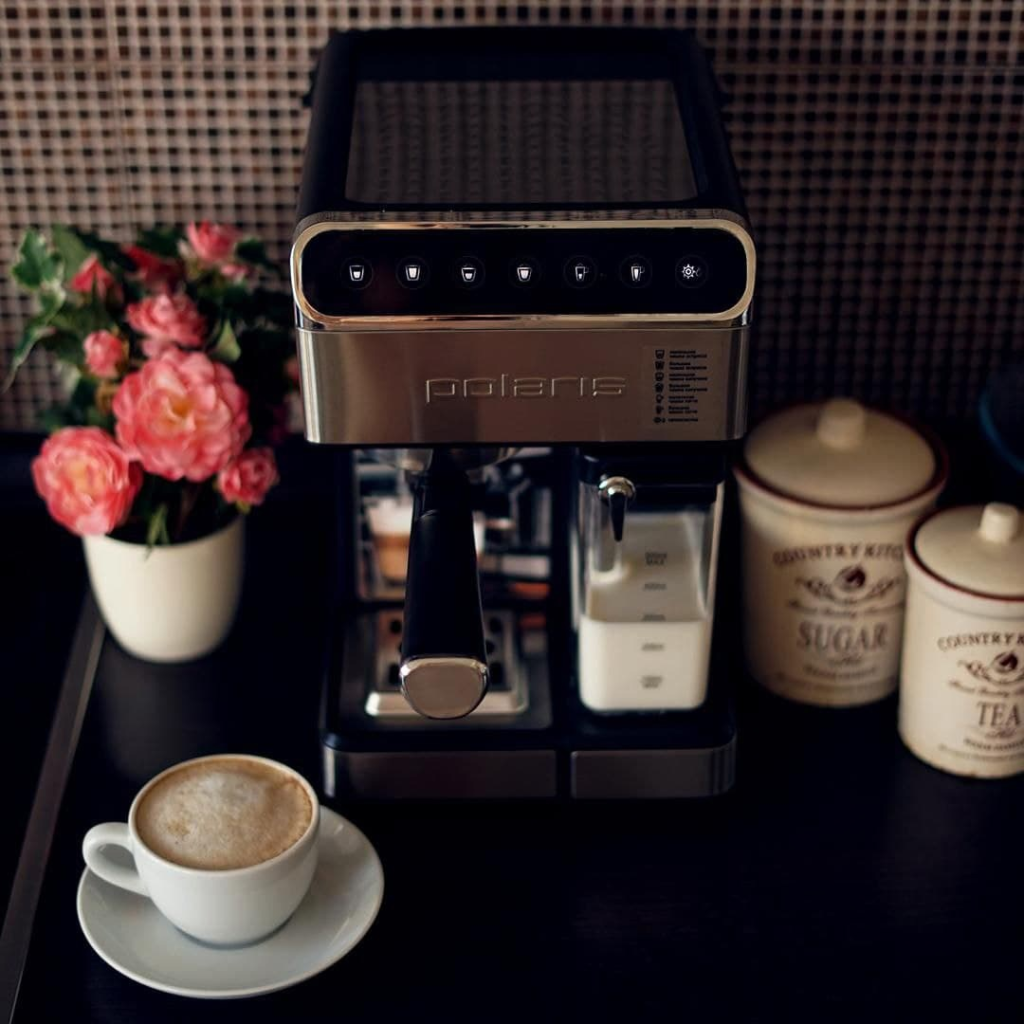 Кофеварка Polaris на столе вместе с чашкой кофе
